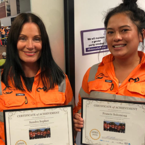 Women in Construction - image of two female graduates wearing high vis shirts and certificates of achievement